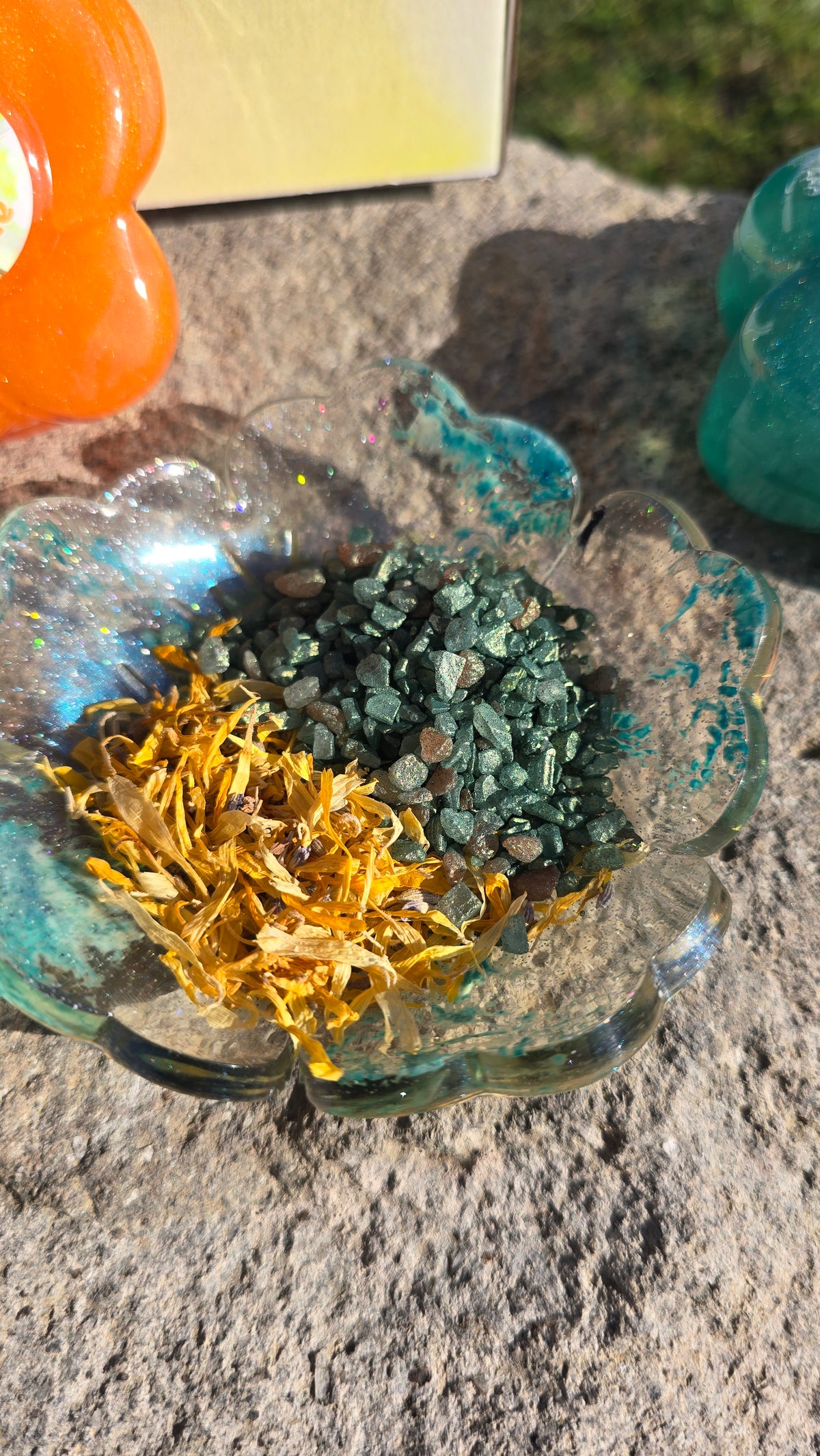 Glass bowl filled with teal, gold, and dark green potion crystals and shimmer