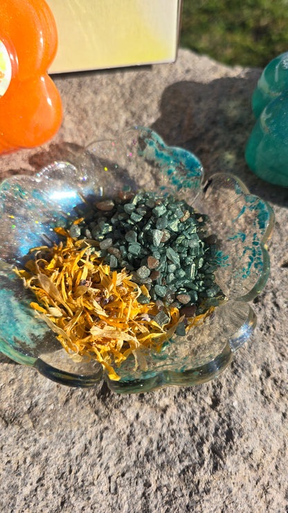 Glass bowl filled with teal, gold, and dark green potion crystals and shimmer